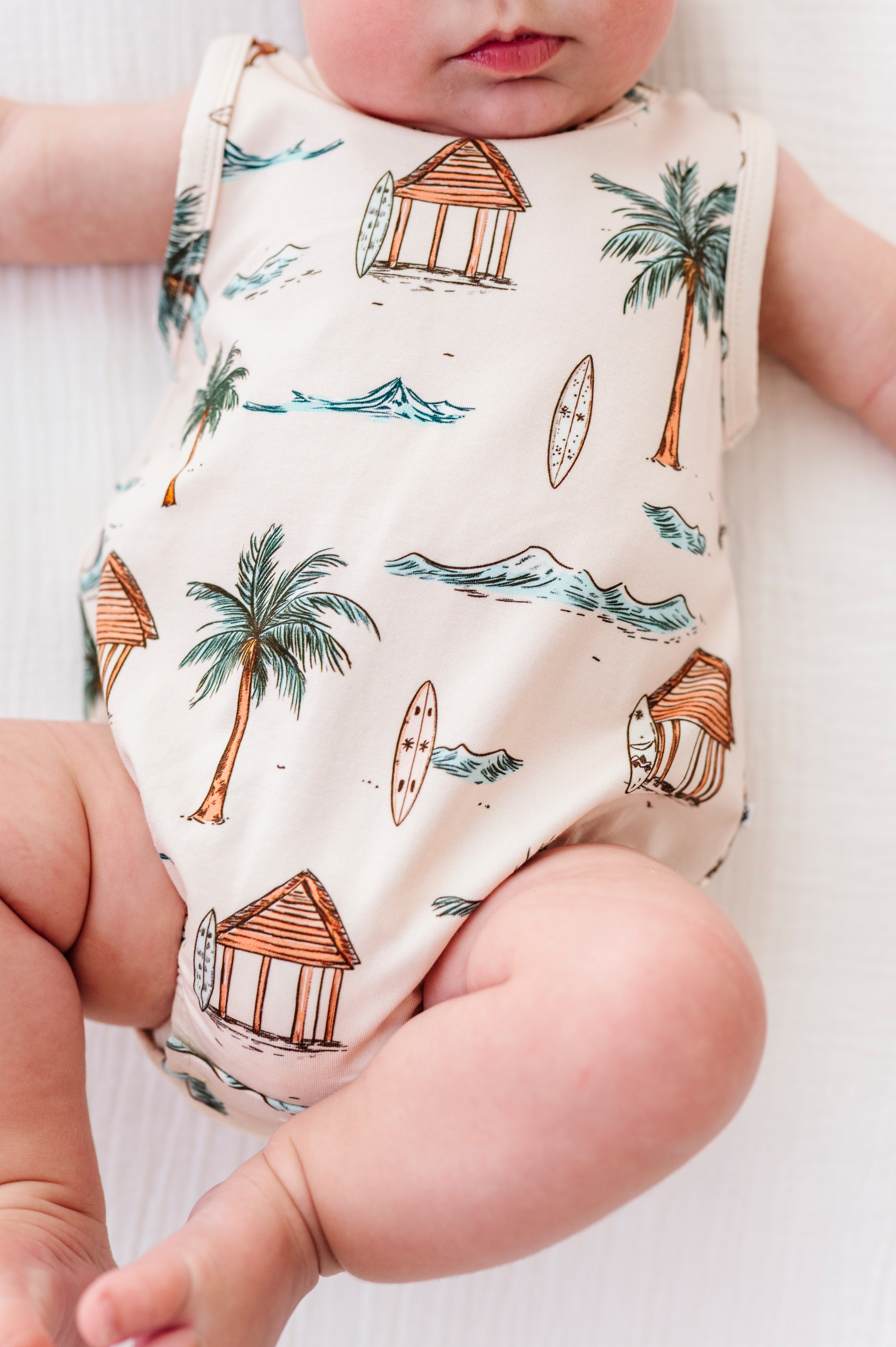 Baby wearing a sleeveless onesie with beach-themed print