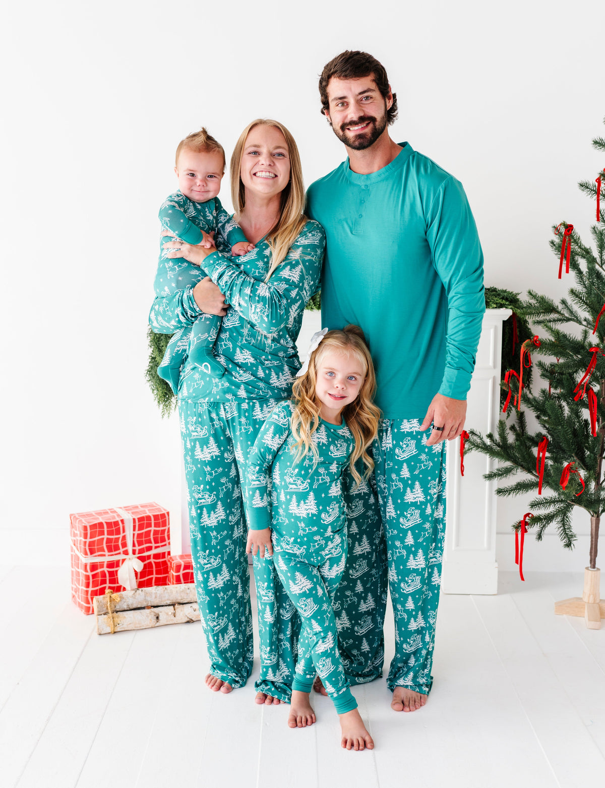 A family wearing matching bamboo pajamas featuring a vintage portrait of Santa and his reindeer 