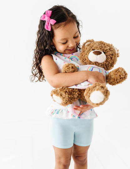 Little girl and her bear wearing matching bamboo watercolor rainbow styles 
