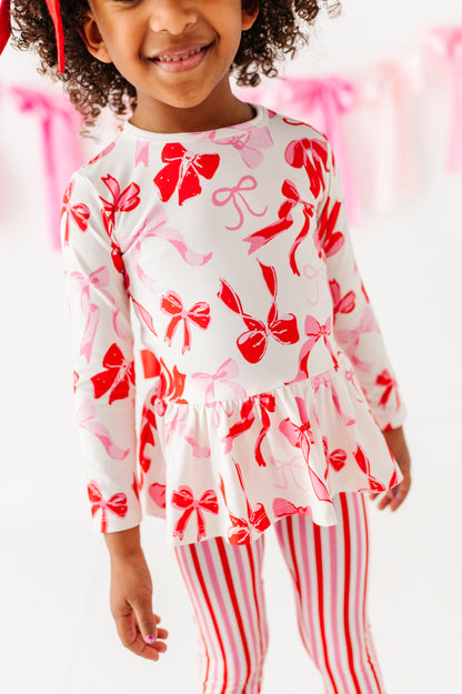 Girl standing in Blushing Bows peplum top and pink striped bottoms