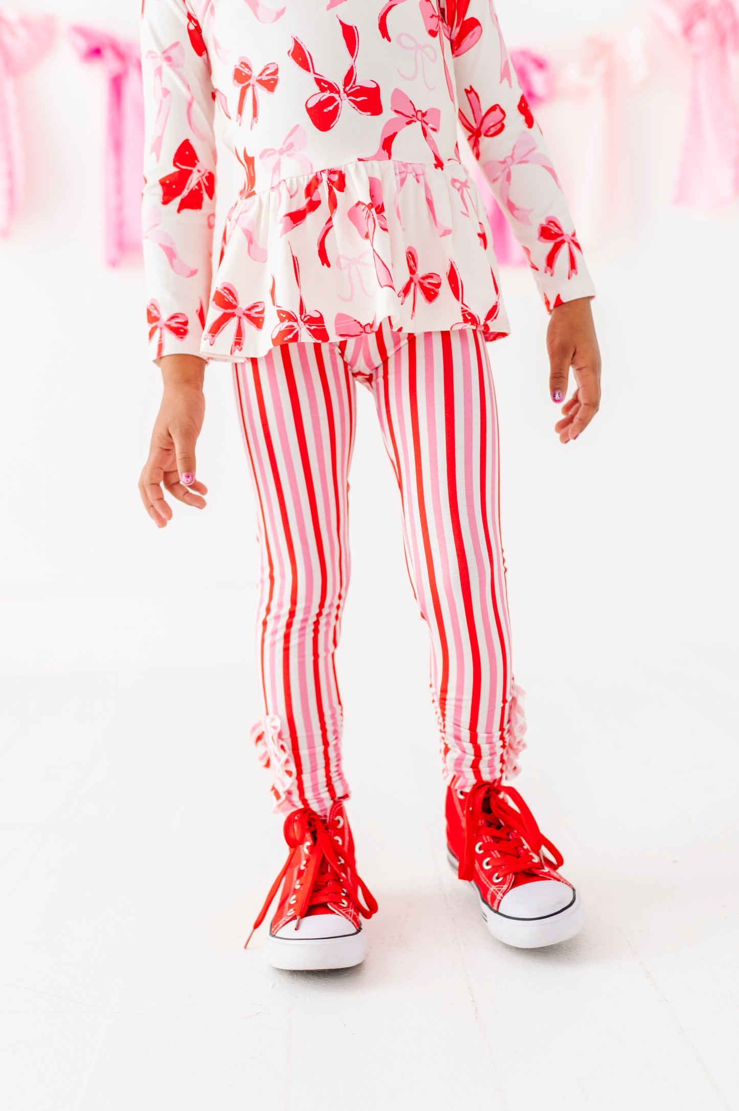 Child wearing red and pink striped bamboo ruffle leggings with peplum top