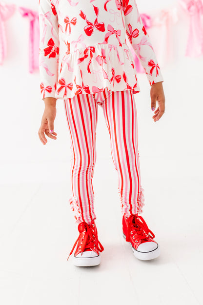 Child wearing red and pink striped bamboo ruffle leggings with peplum top
