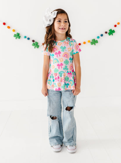 Young girl wearing a colorful bamboo cotton peplum top and ripped jeans with a white background  decorated for St. Patrick's Day