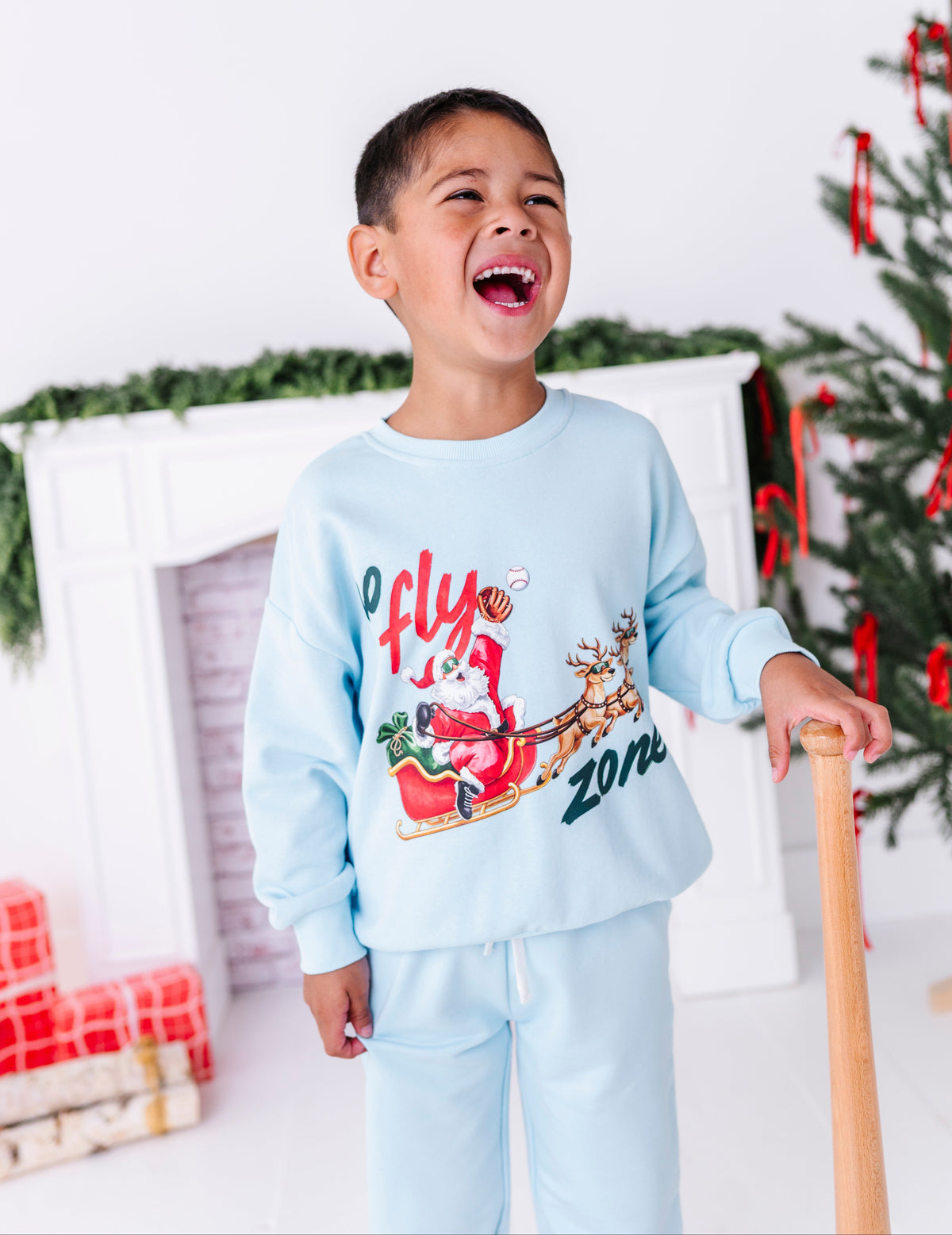 A little boy laughing to himself while wearing a baseball crewneck 