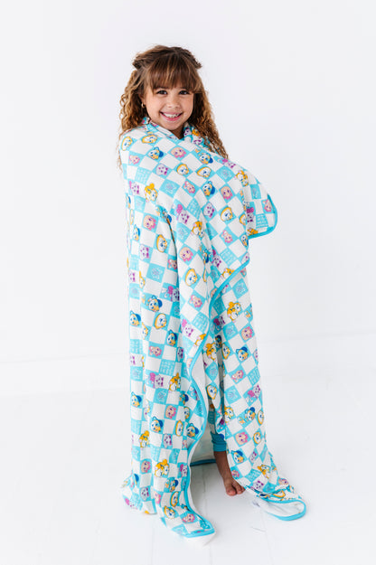 Child wrapped in a 44 Cats bamboo blanket on a white background 