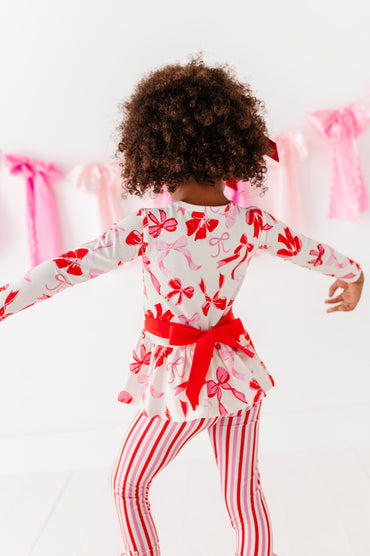 Back view of Blushing Bows peplum top showing statement red bow detail
