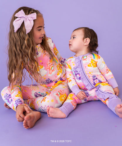 Two children wearing colorful pajamas sitting on a purple floor.