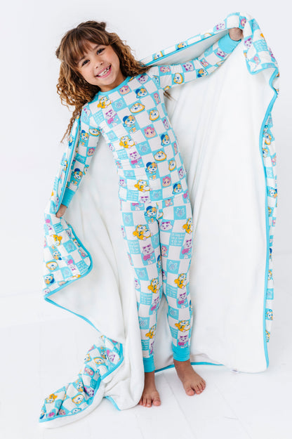Child wrapped in a colorful 44 Cats bamboo blanket on a white background