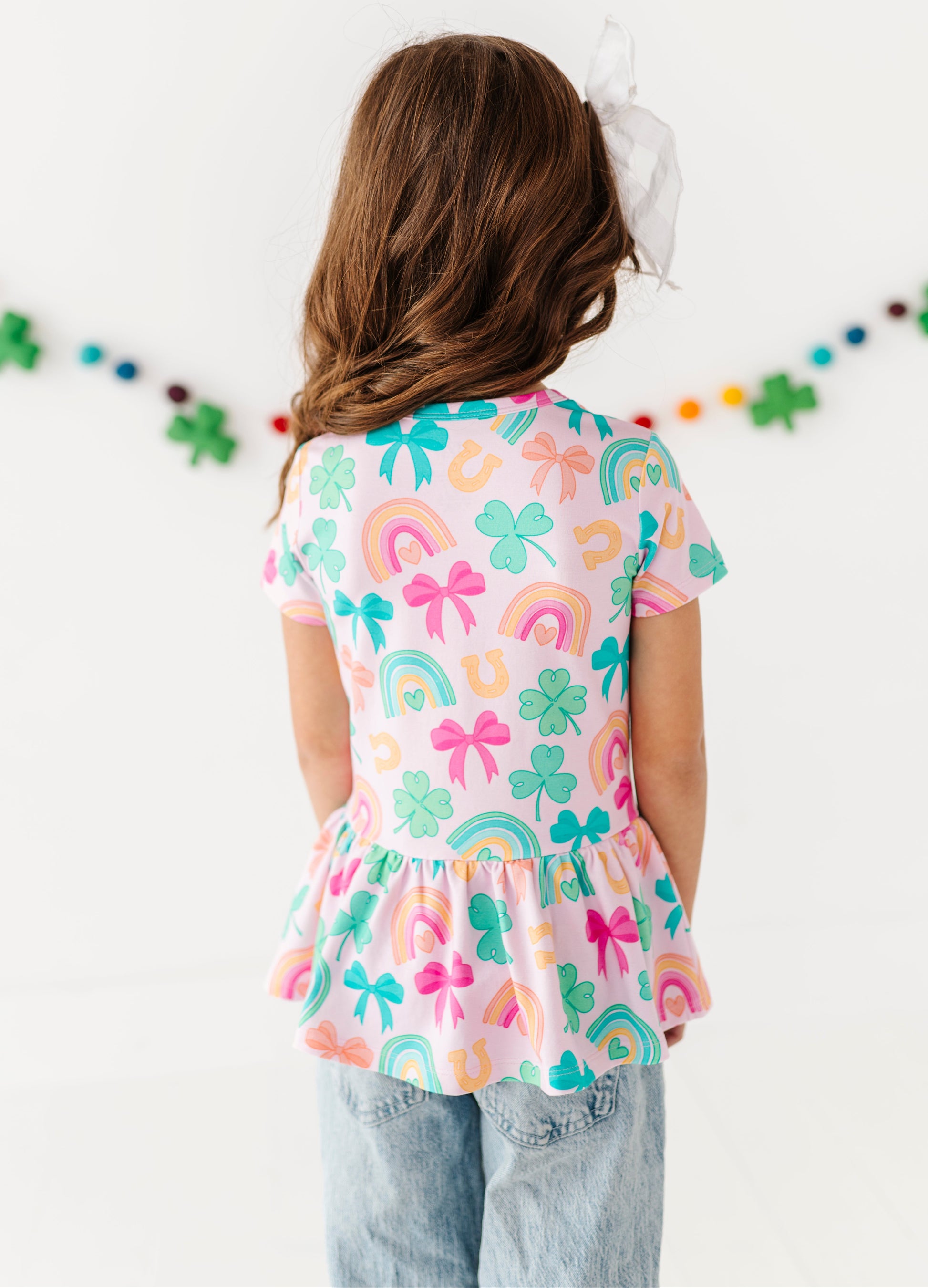 Back view of a bamboo cotton St. Patrick's Day themed peplum top with light wash denim 