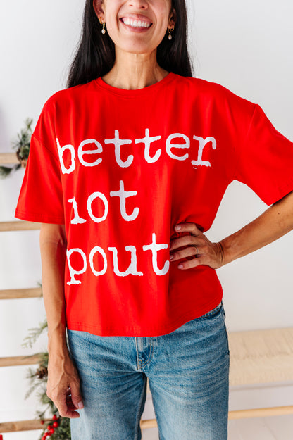 A woman wearing a bright red oversized graphic t-shirt with the text 'better not pout' in white distressed lettering, paired with blue jeans.
