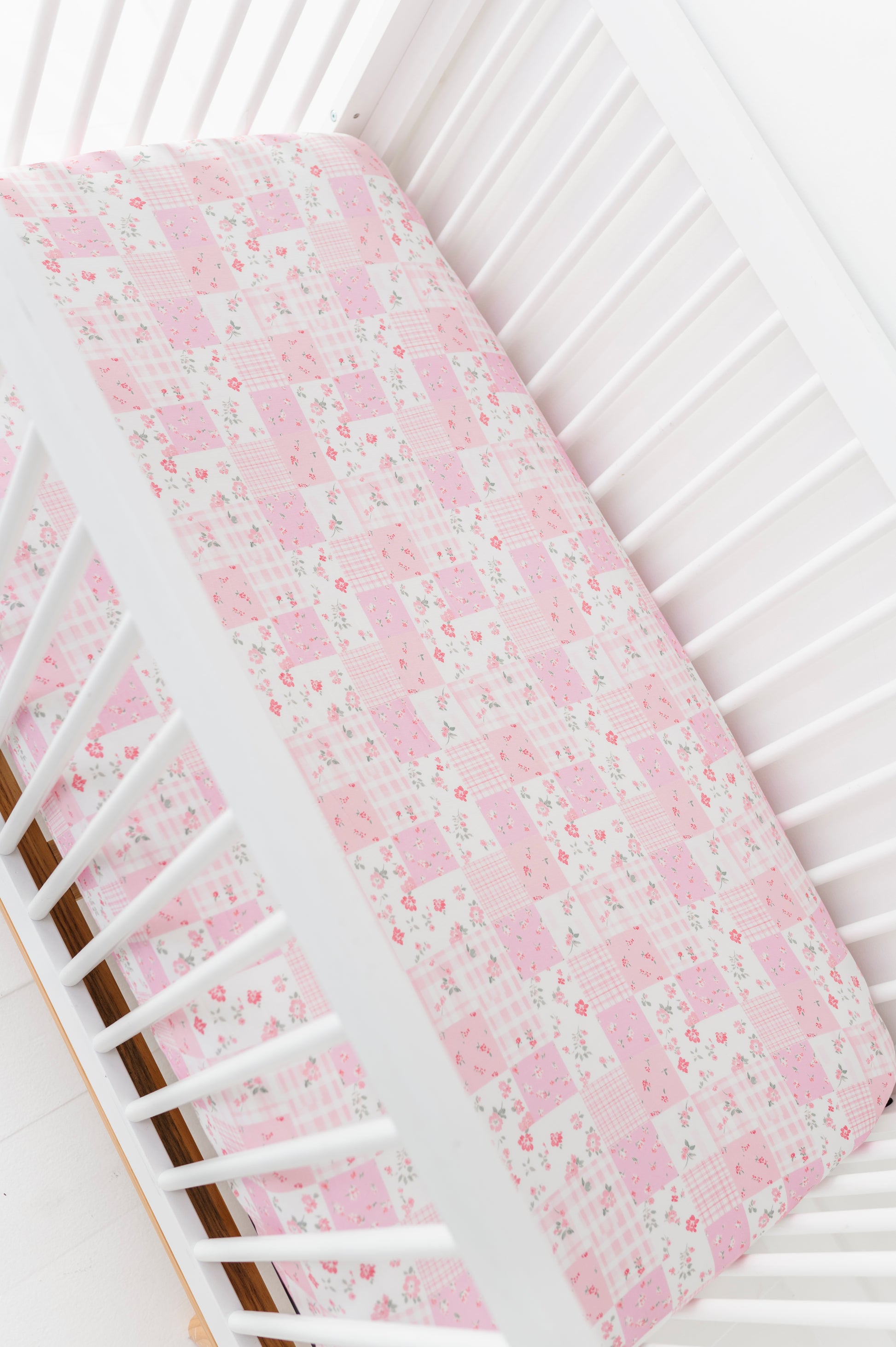 Floral-patterned bamboo pink crib sheet on a white crib