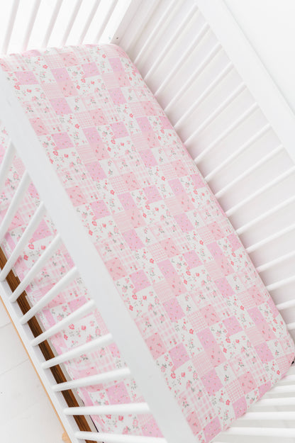 Floral-patterned bamboo pink crib sheet on a white crib