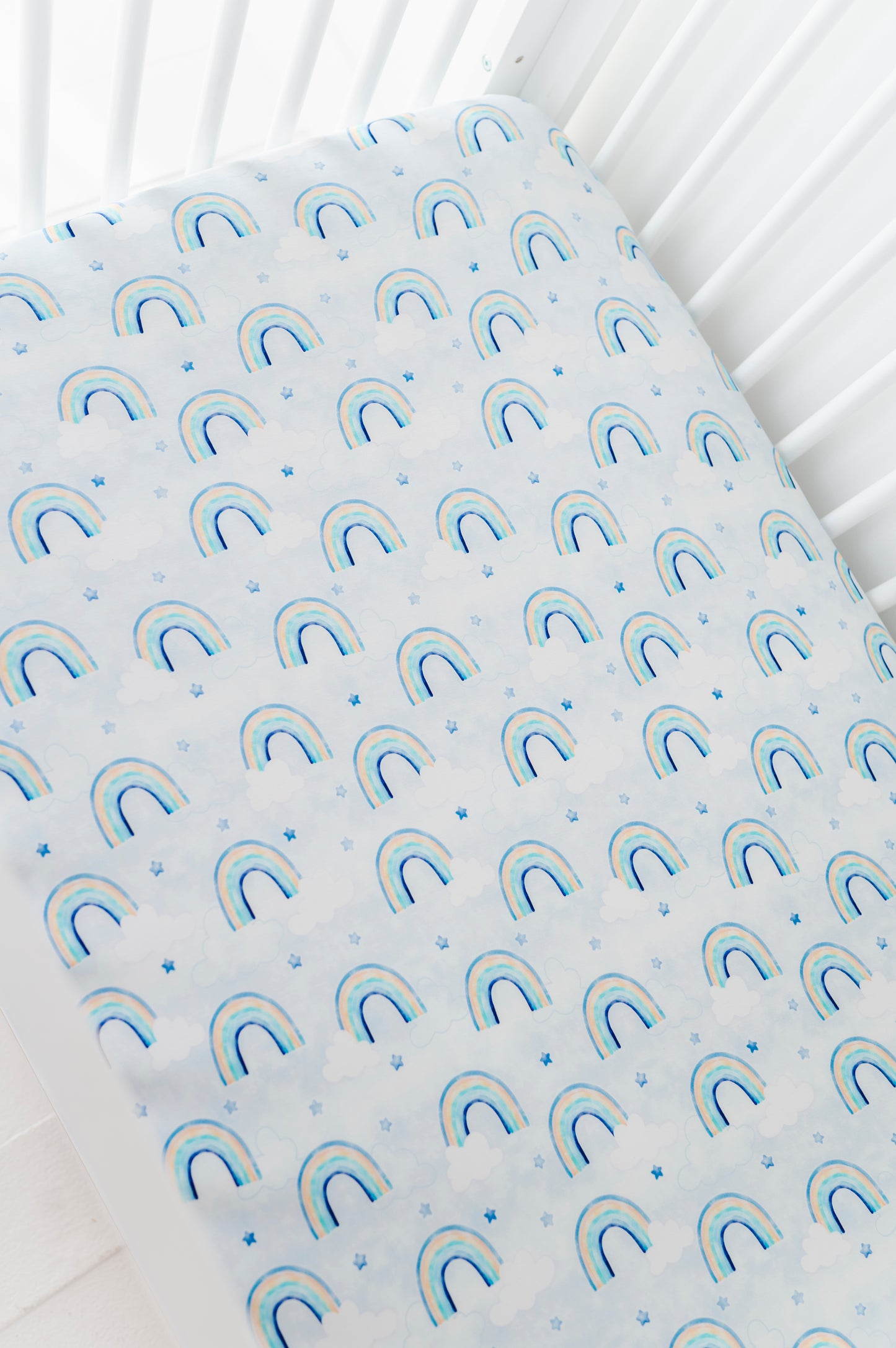 Fitted bamboo crib sheet with watercolor rainbow pattern on a white crib