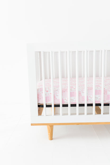 White crib with a pink bamboo crib sheet on a white background