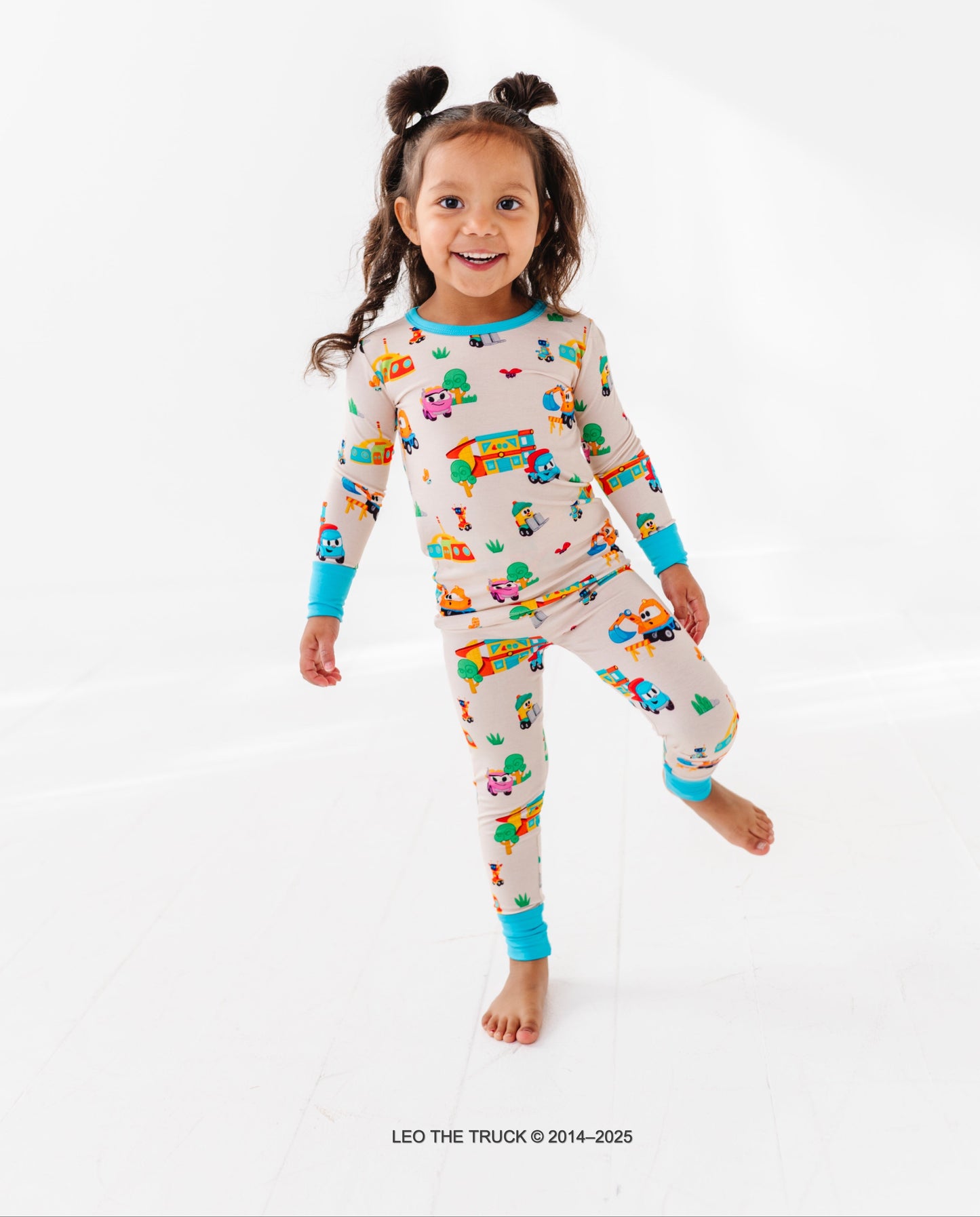 Toddler wearing colorful Leo the Truck bamboo pajamas on a white background