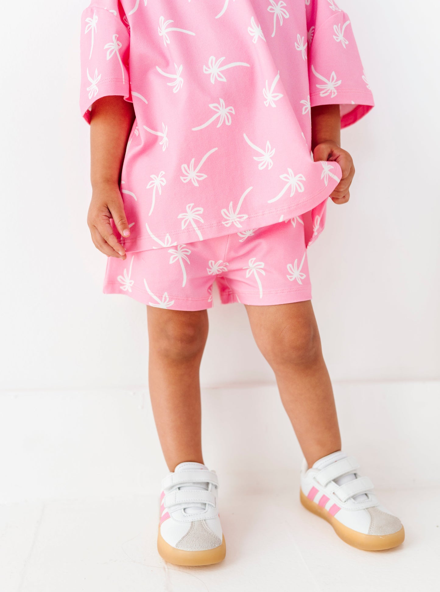 Child wearing a pink outfit with white patterns on a white background