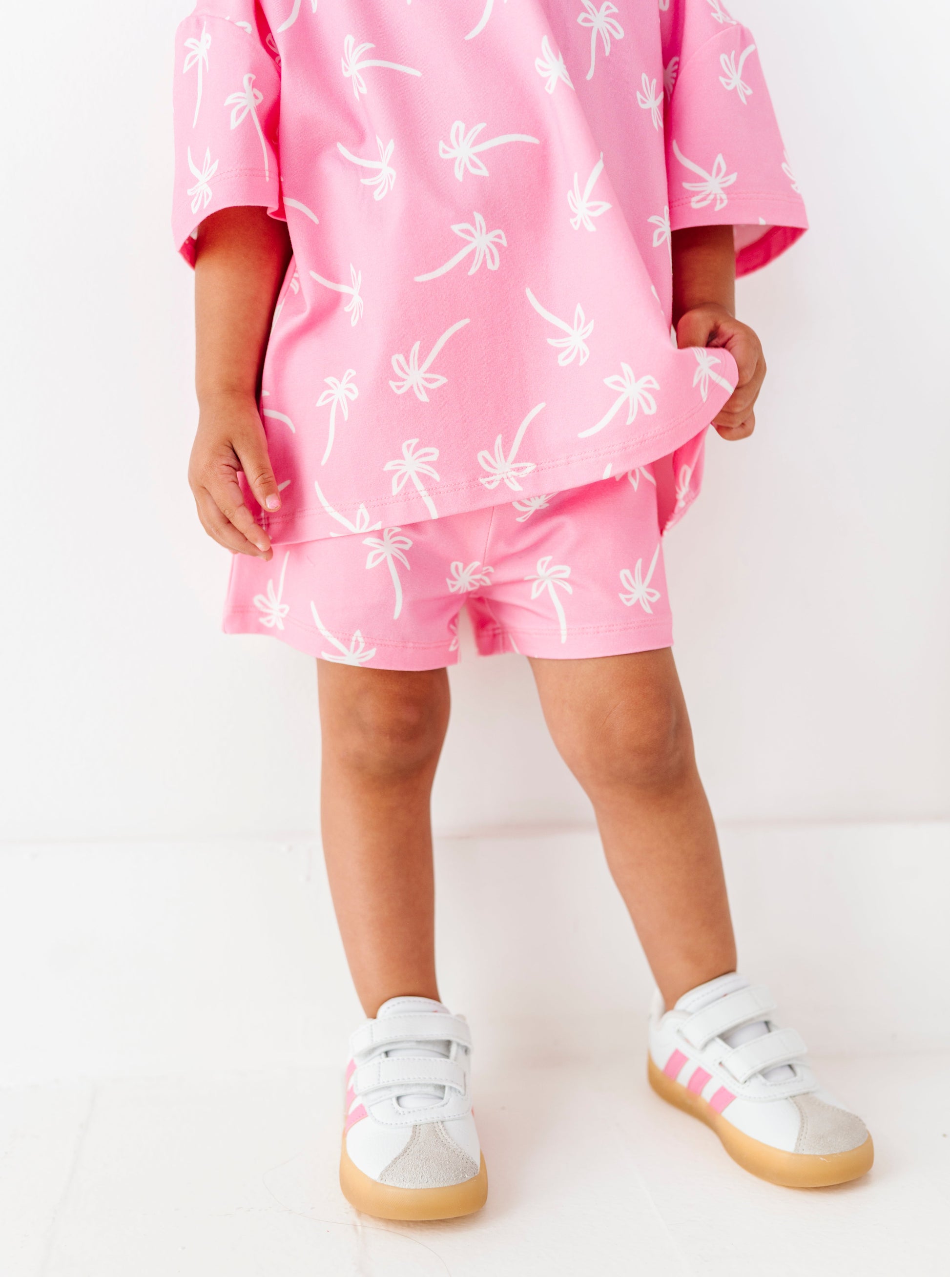 Child wearing a pink outfit with white patterns on a white background