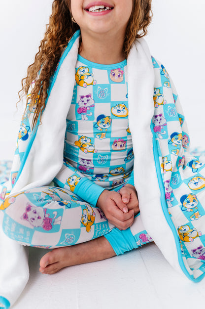 Child wearing a bamboo 44 Cats pajama set with cartoon cats and a matching plush bamboo blanket.