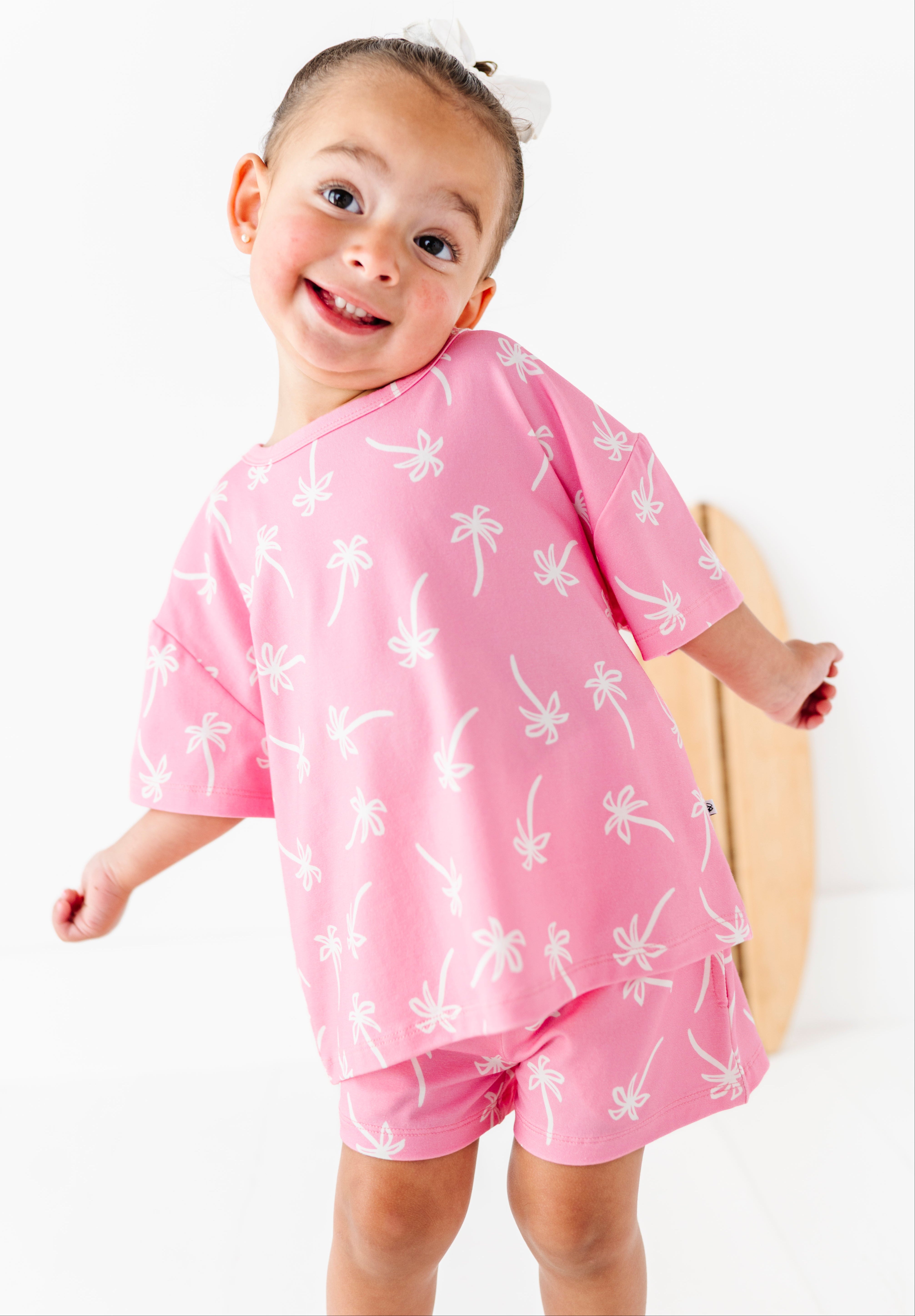 Child wearing a pink outfit with white patterns on a white background