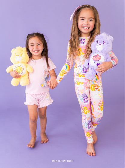 Two children holding Care Bears™plush toys against a purple background