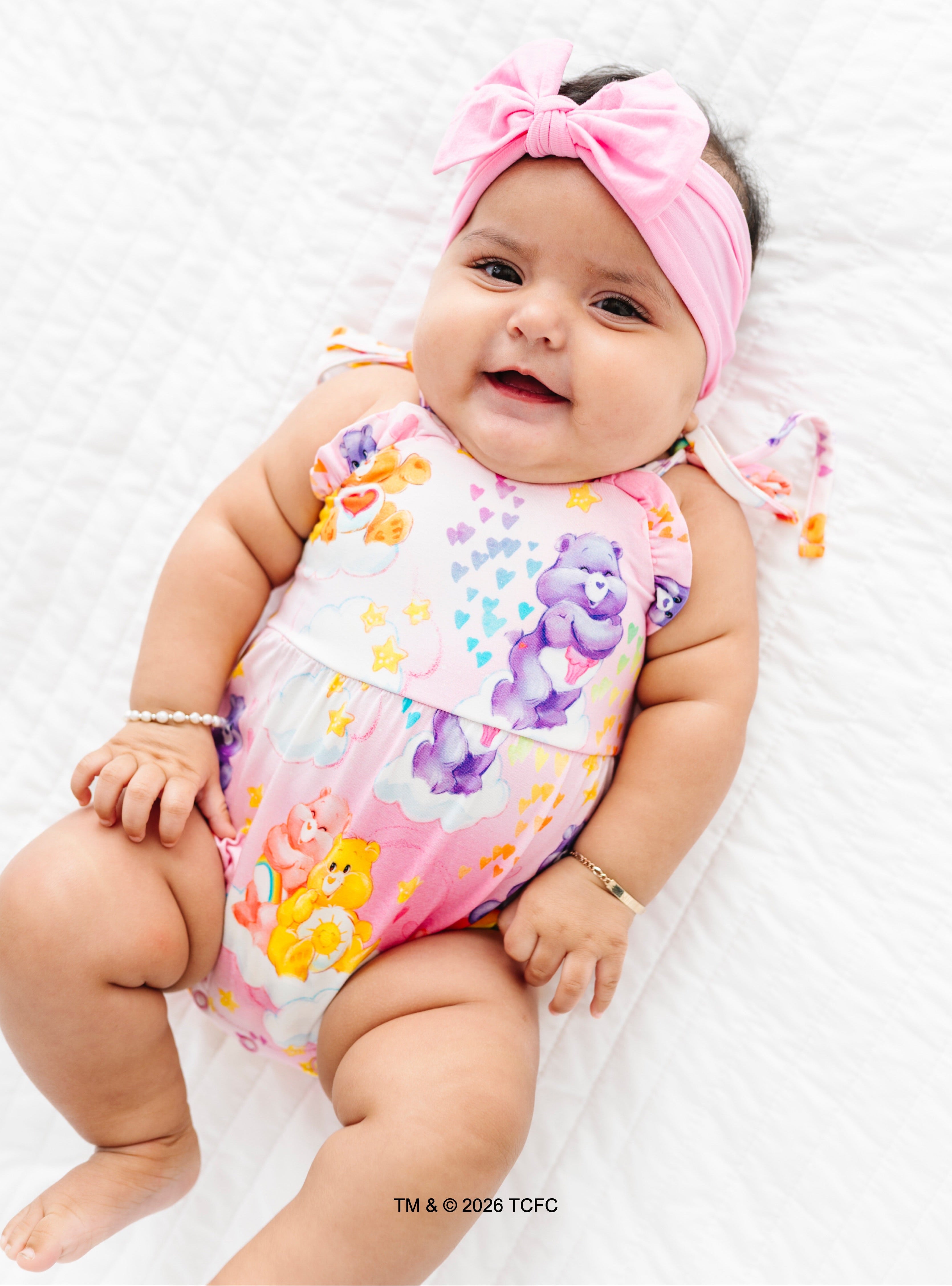 Baby wearing a colorful ROMPER with cartoon characters on a white background