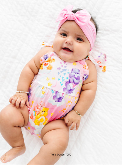 Baby wearing a colorful bamboo bubble romper with Care Bears™ on a white background