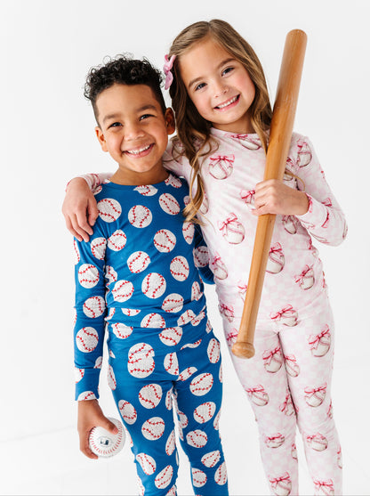 Siblings wearing bamboo pajamas with sports-themed prints, one holding a baseball bat.