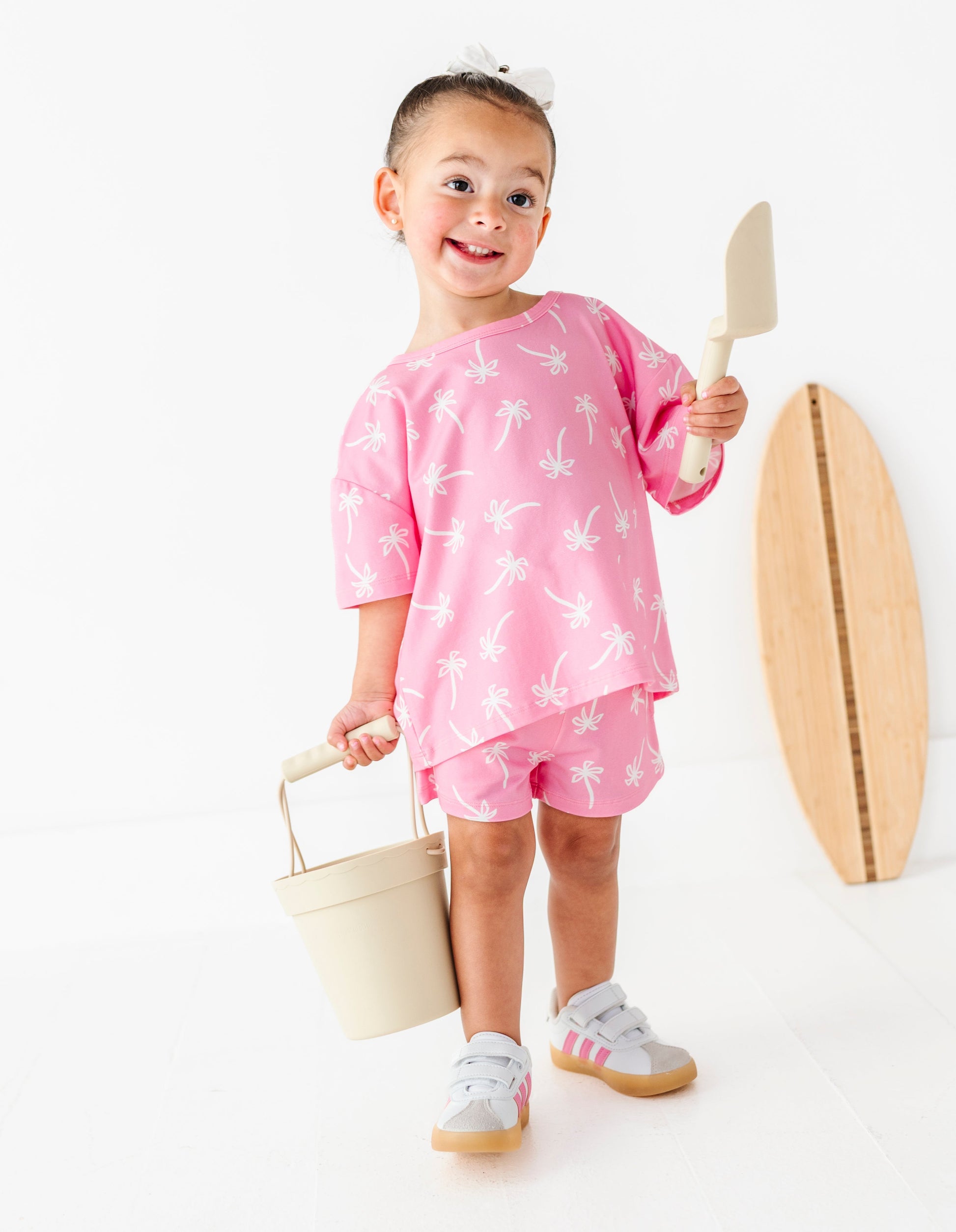 Child in pink outfit with beach accessories on a white background