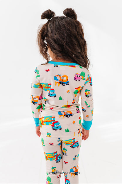 Little girl wearing colorful Leo the Truck bamboo pajamas on a white background