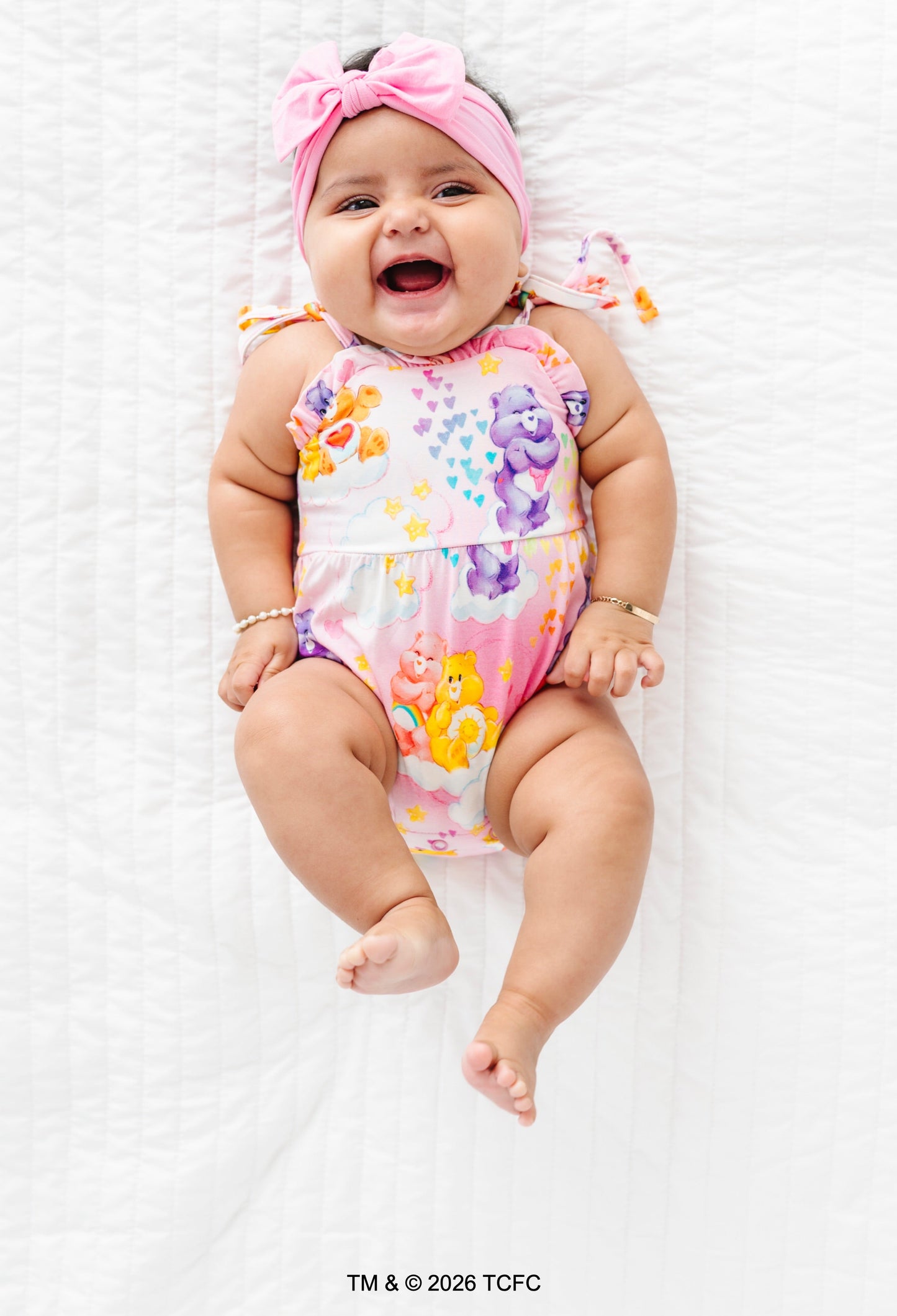 Baby wearing a colorful Care Bears™ bubble romper on a white background