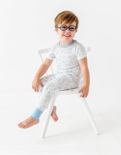 Child wearing glasses and a light-colored bamboo Easter pajama set sitting on a chair against a white background