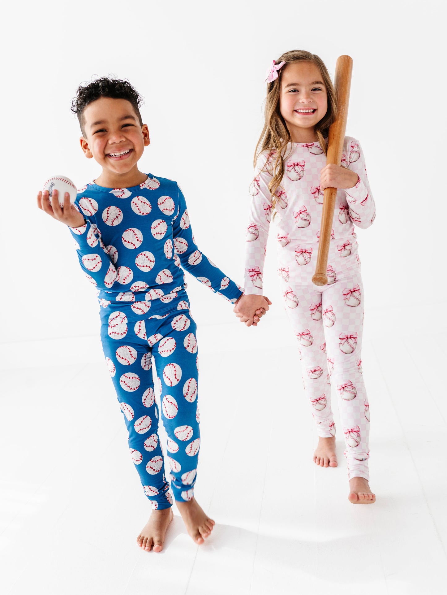Two children wearing bamboo pajamas with baseball-themed prints on a white background