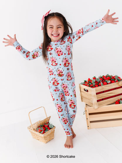 Child wearing a Strawberry Shortcake™ two-piece set with a white background and strawberry-themed props.