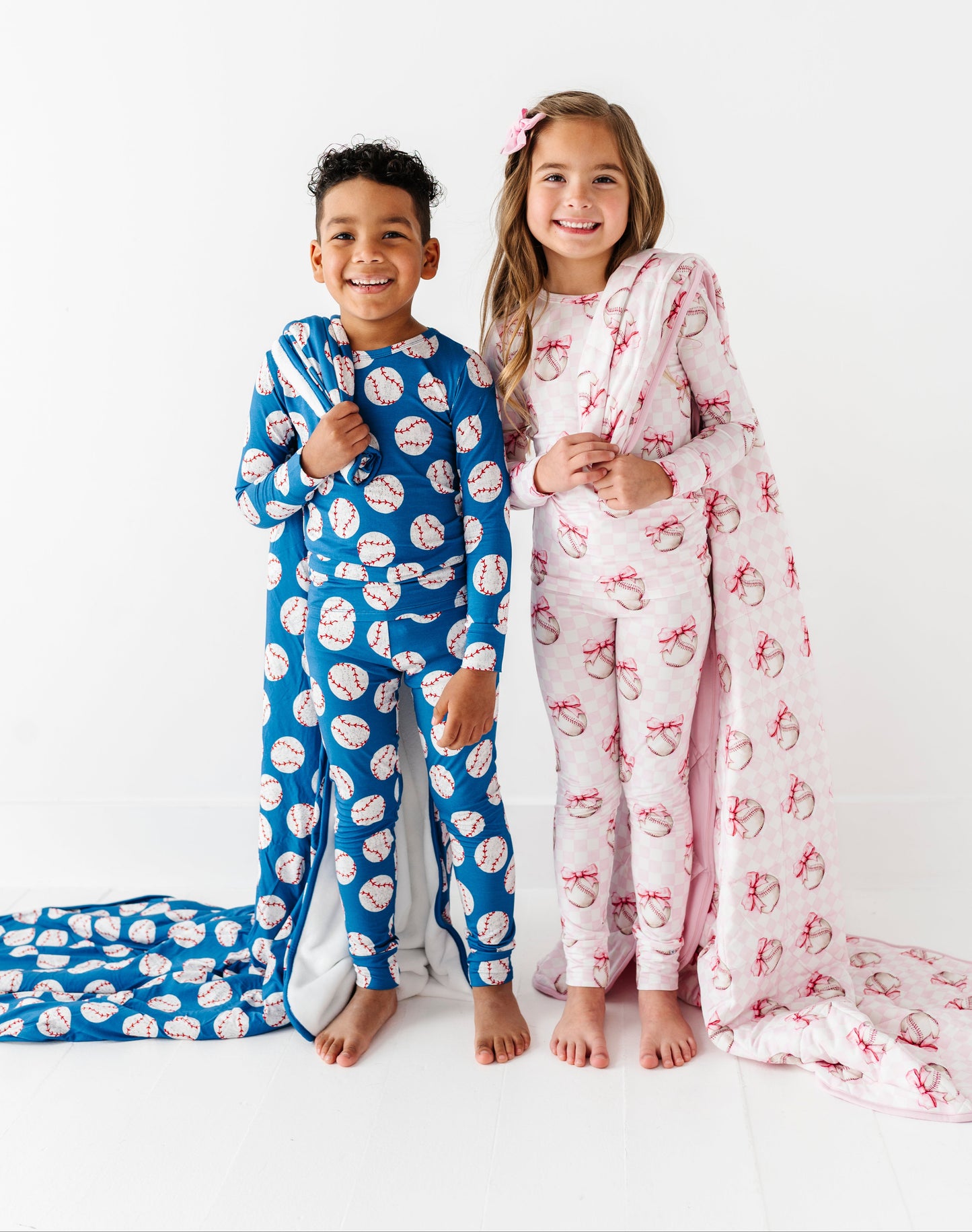 Siblings wearing matching bamboo pajamas and holding baseball blankets 
