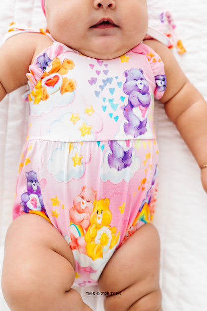 Baby wearing a colorful Care Bears™ bubble romper on a white background