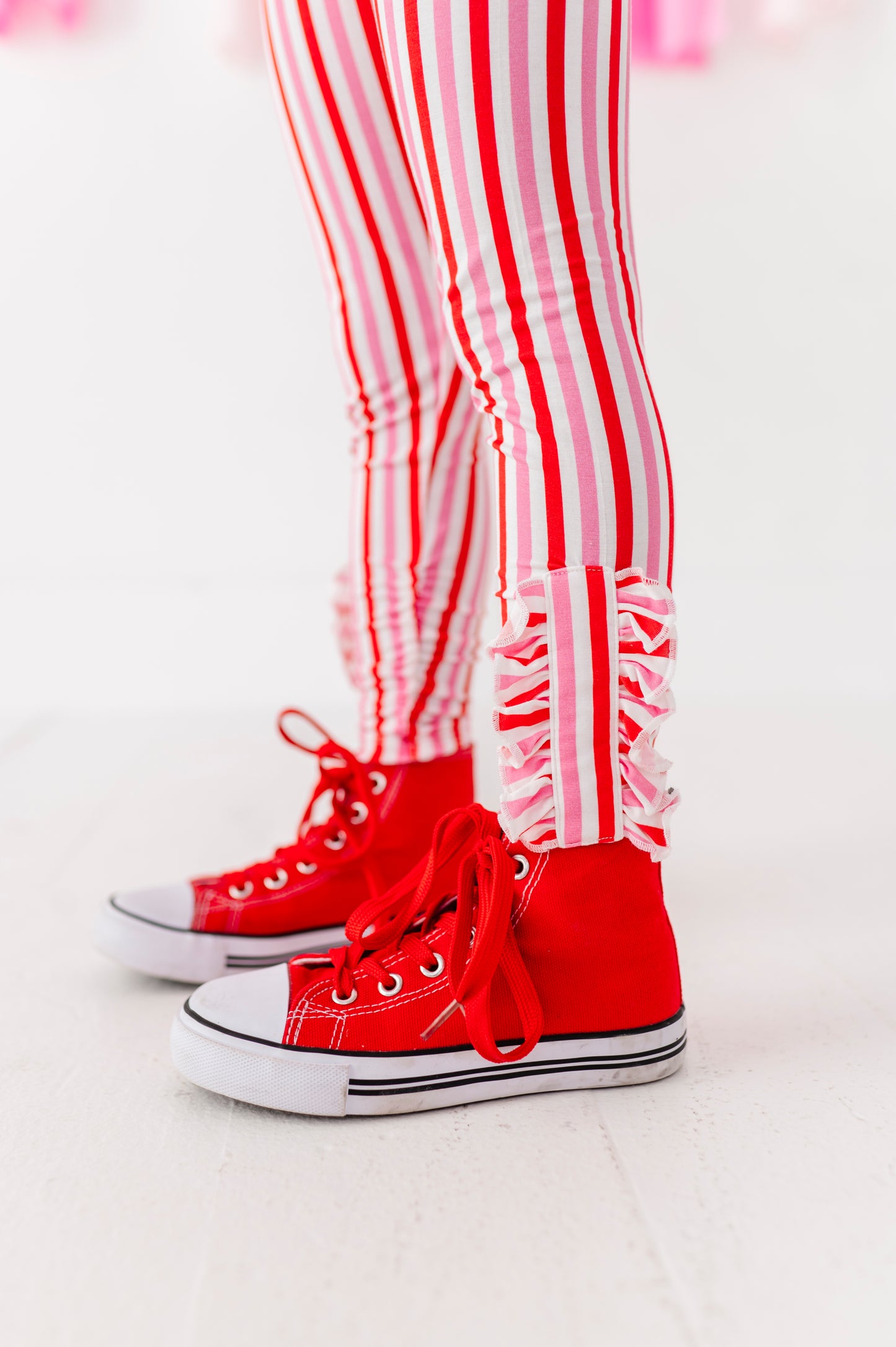 Close-up of red and pink striped leggings showing ruffle ankle detail