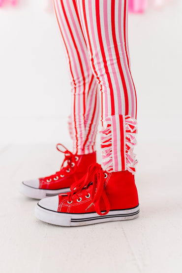 Close-up of red and pink striped leggings showing ruffle ankle detail