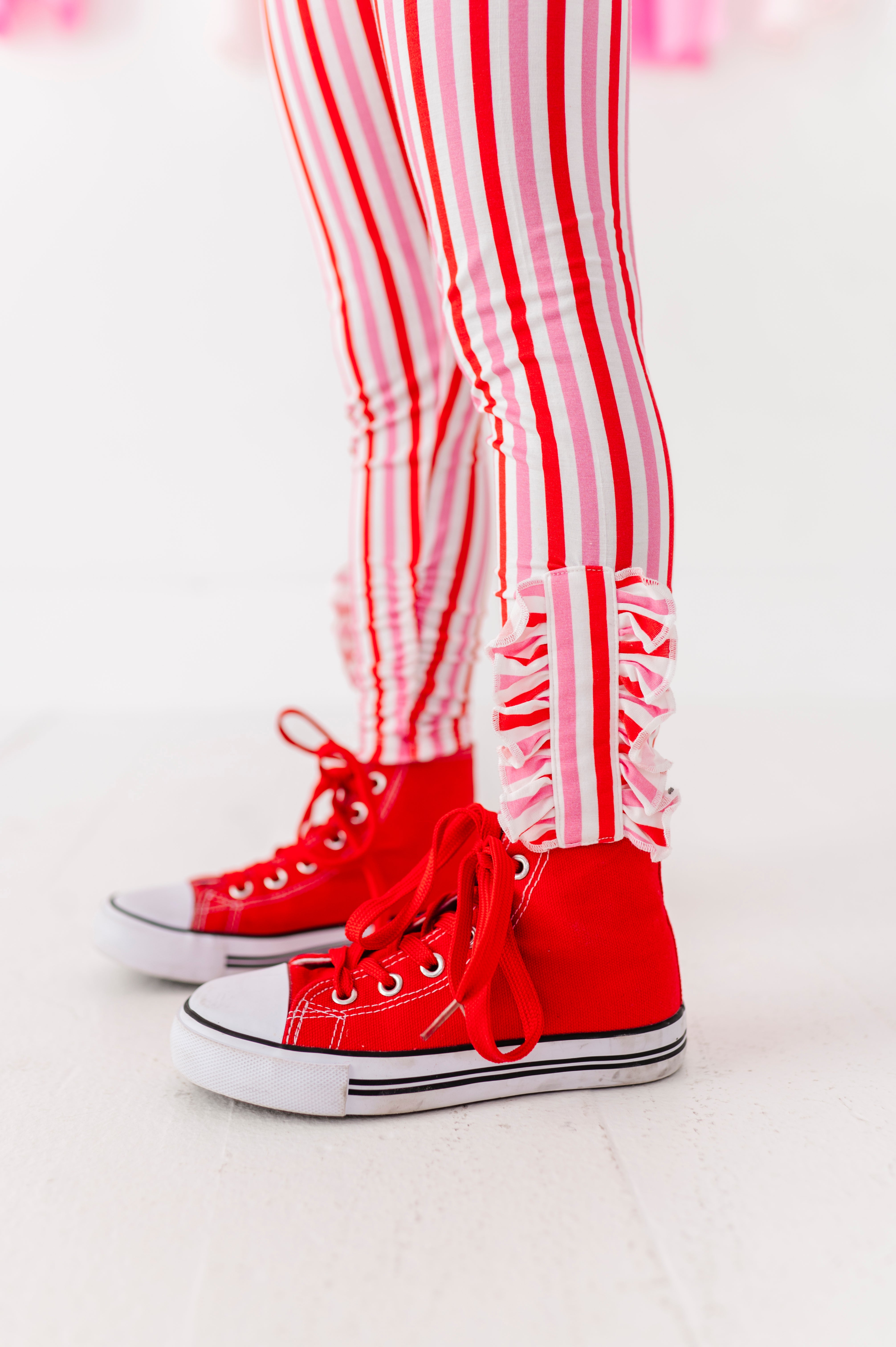 Close-up of red and pink striped leggings showing ruffle ankle detail