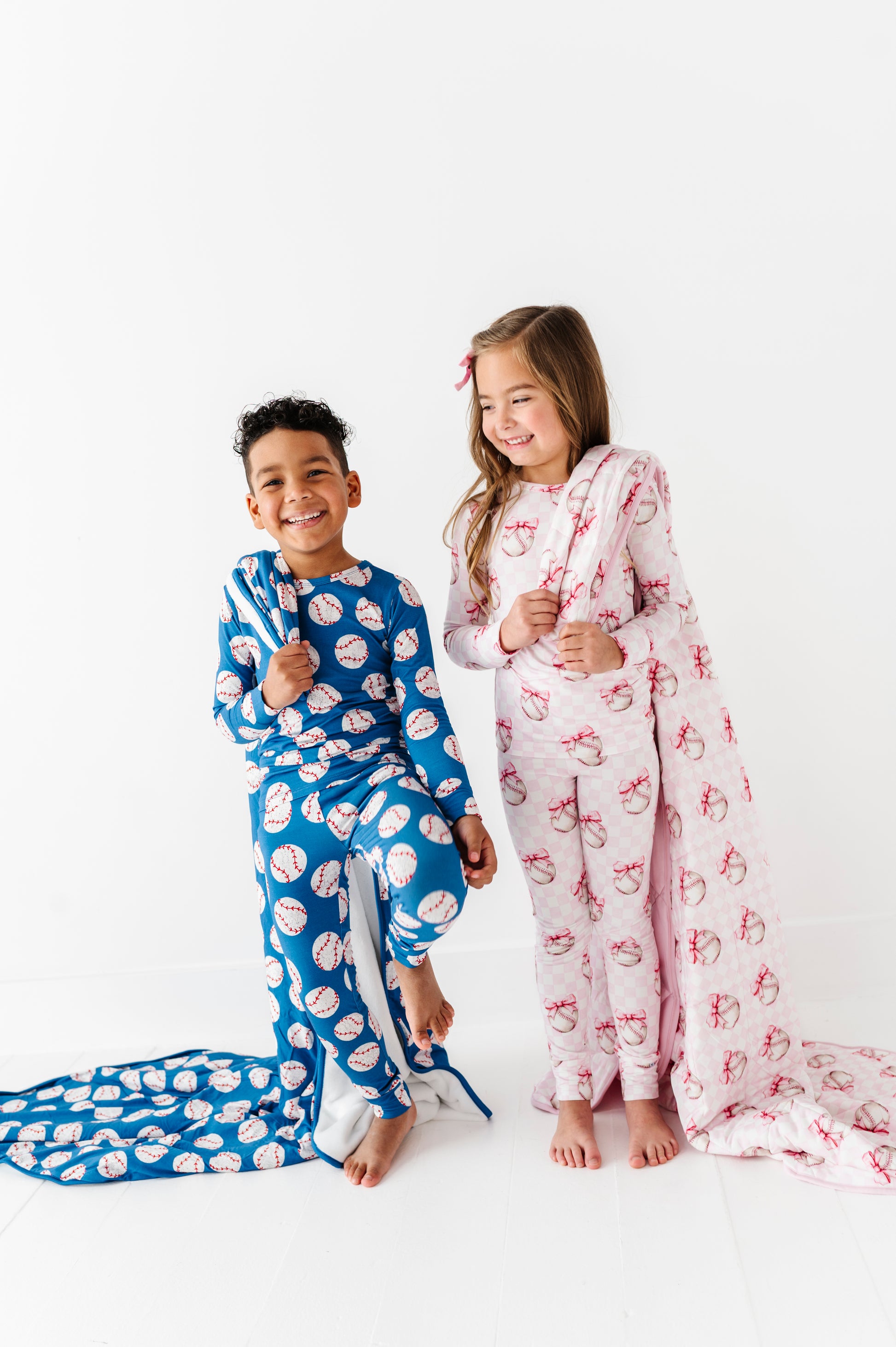Two children wearing coordinating baseball pajamas on a white background