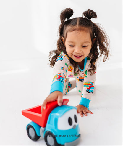 Little girl playing with a Leo the Truck toy against a white background 
