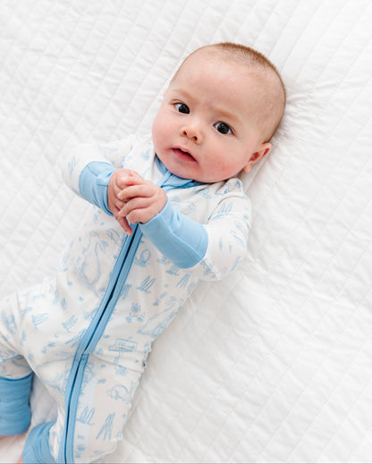 Baby wearing  a white and blue Easter bamboo romper lying on a white textured surface