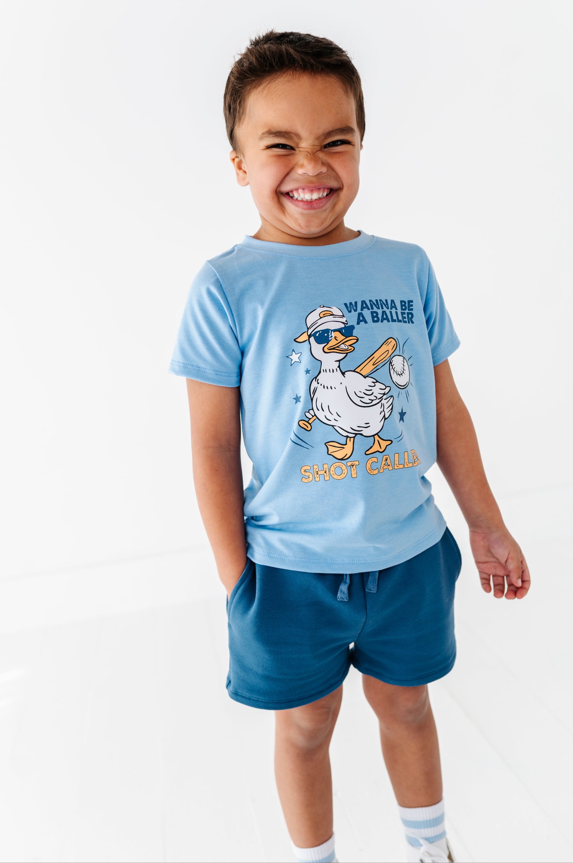 Child wearing a blue baseball t-shirt with a cartoon duck design on a white background