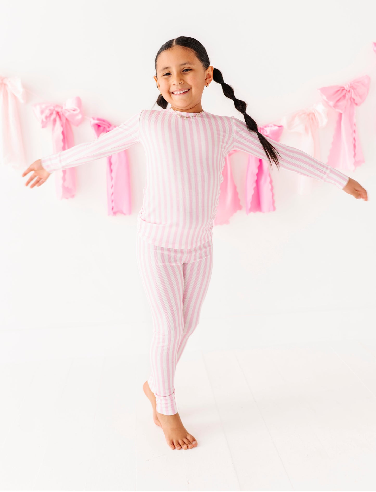 Child wearing pink striped two-piece bamboo pajamas
