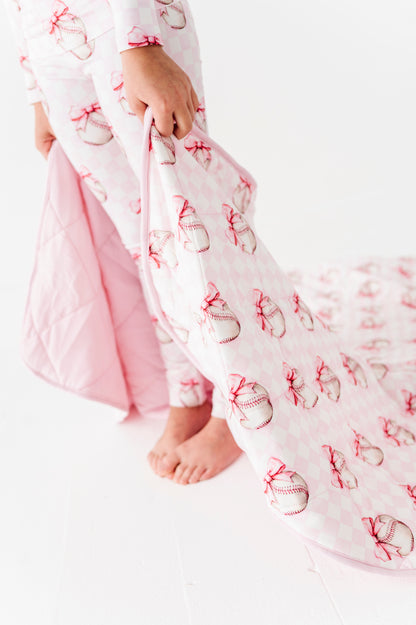 Child wearing a pink and white baseball outfit on a white background
