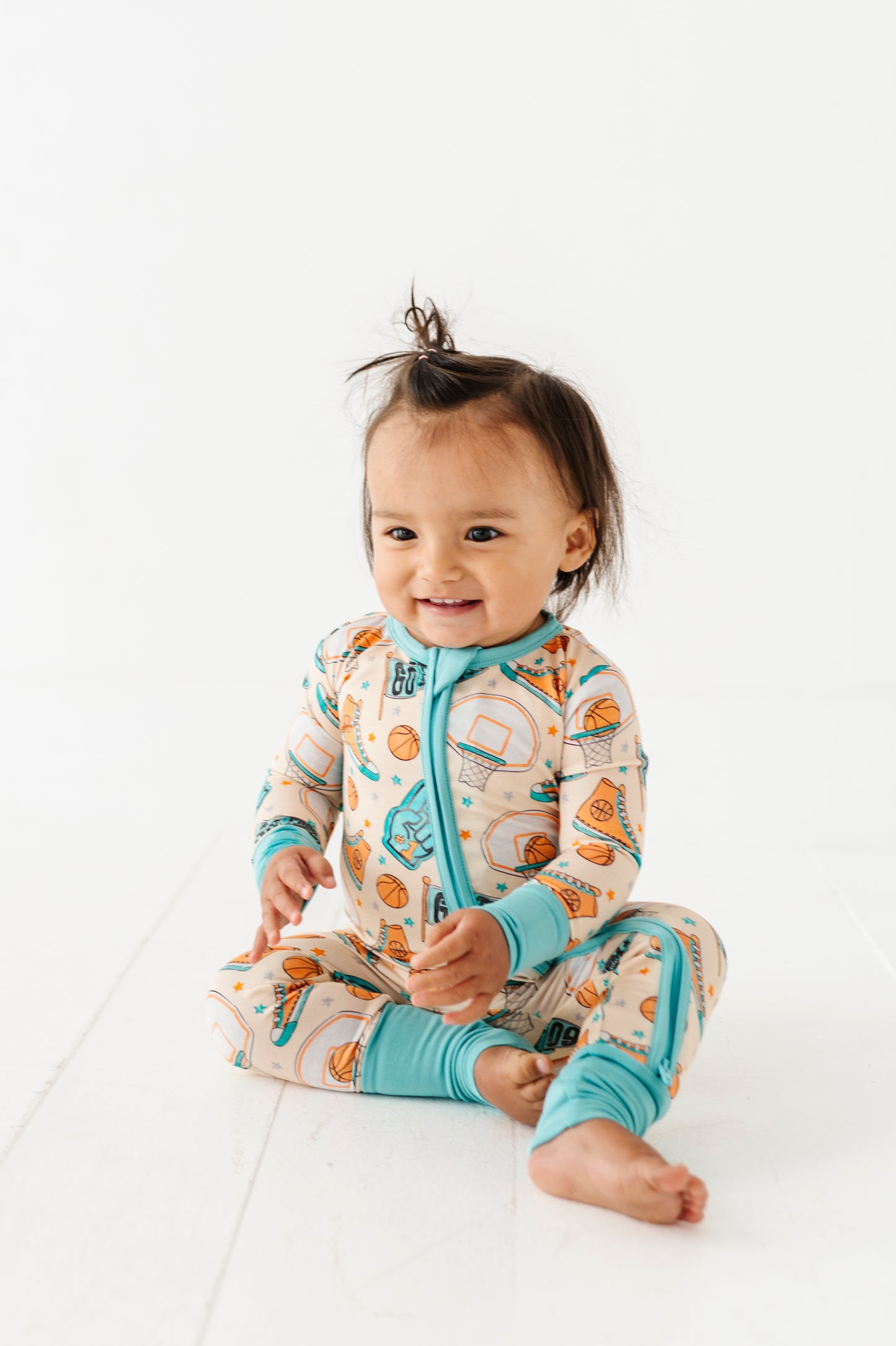 Child wearing a sports themed bamboo onesie with a zipper on a white background