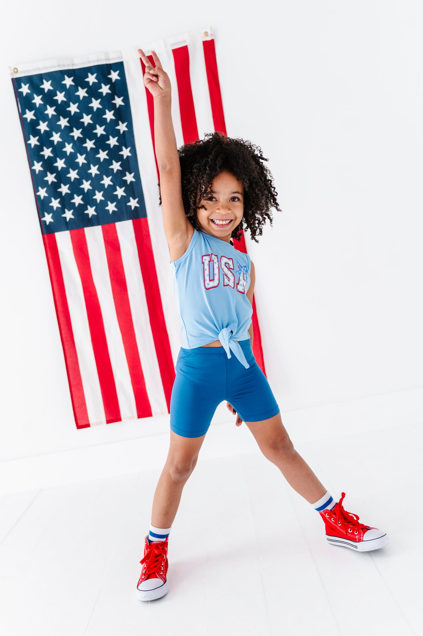 Child in patriotic outfit with American flag in the background