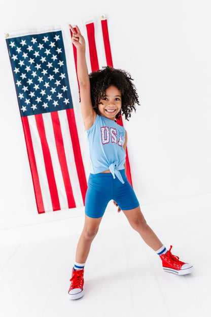 Child in patriotic outfit with American flag in the background