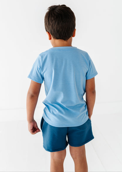 Child wearing a blue baseball t-shirt and shorts on a white background