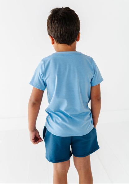 Child wearing a light blue t-shirt and dark blue bamboo cotton shorts on a white background