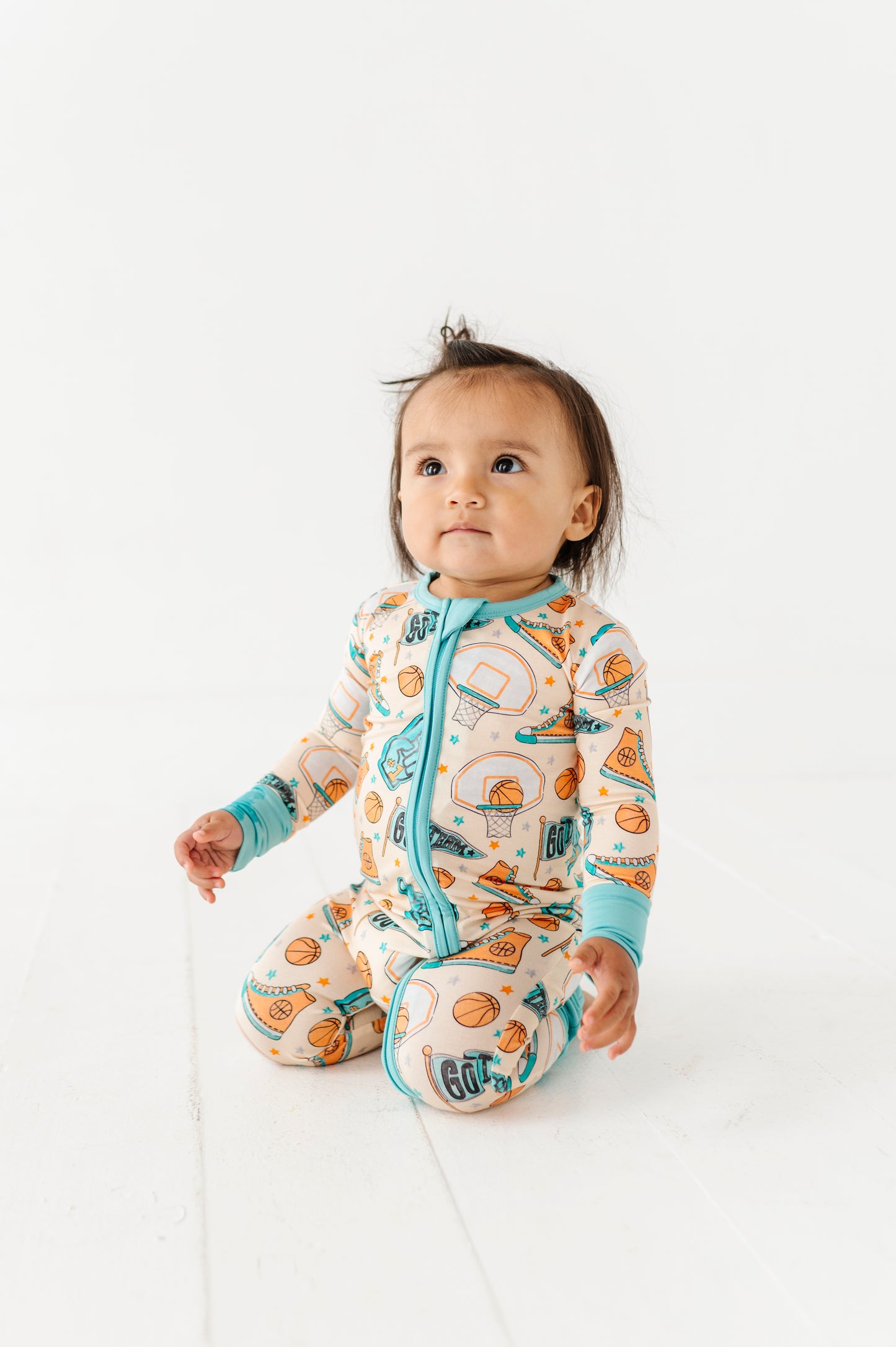 Baby wearing a convertible romper with a sports theme on a white background